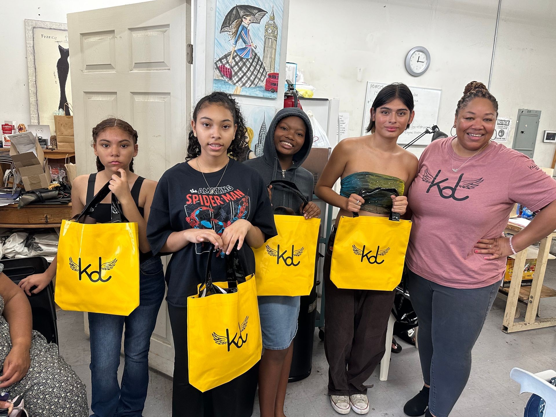 Group of people standing indoors holding yellow bags with a logo, smiling at the camera.